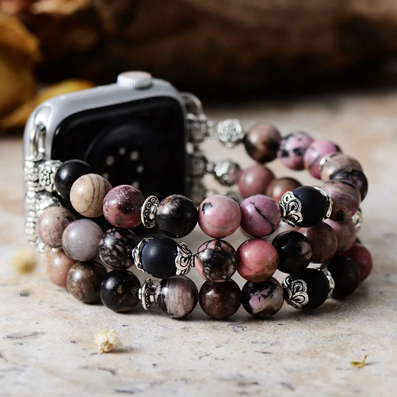 Stack of multicolored beaded bracelets on a wooden surface with a blurred background. Black Rhodonite Stretchy Apple Watch Band | ALLORA JADE