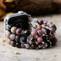 Stack of multicolored beaded bracelets on a wooden surface with a blurred background. Black Rhodonite Stretchy Apple Watch Band | ALLORA JADE