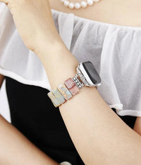 Close-up of a wrist wearing a smartwatch with a decorative band, against a white shirt background. Smartwatch with a decorative band on a wooden surface. Earthy Jasper Stretchy Apple Watch Band | ALLORA JADE