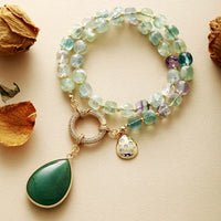 Multicolored beaded necklace with a green pendant on a beige surface. Green Quartz Pavé Statement Necklace | ALLORA JADE