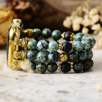 Set of beaded bracelets with gold accents on a marble surface. Gold watch case with green beaded bracelet on a marble surface. African Turquoise Stretchy Apple Watch Band | ALLORA JADE