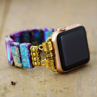 Smartwatch with a decorative gold band on a textured surface. Purple Aqua Jasper Stretchy Apple Watch Band - gold | ALLORA JADE