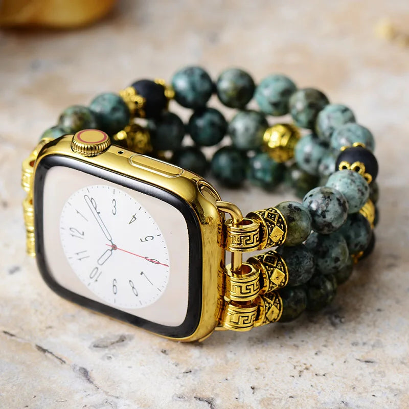 Gold watch case with green beaded bracelet on a marble surface. African Turquoise Stretchy Apple Watch Band | ALLORA JADE
