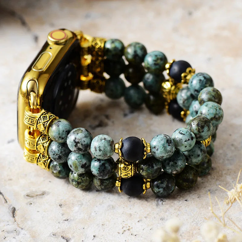 Beaded bracelet with gold accents on a textured surface. Gold watch case with green beaded bracelet on a marble surface. African Turquoise Stretchy Apple Watch Band | ALLORA JADE