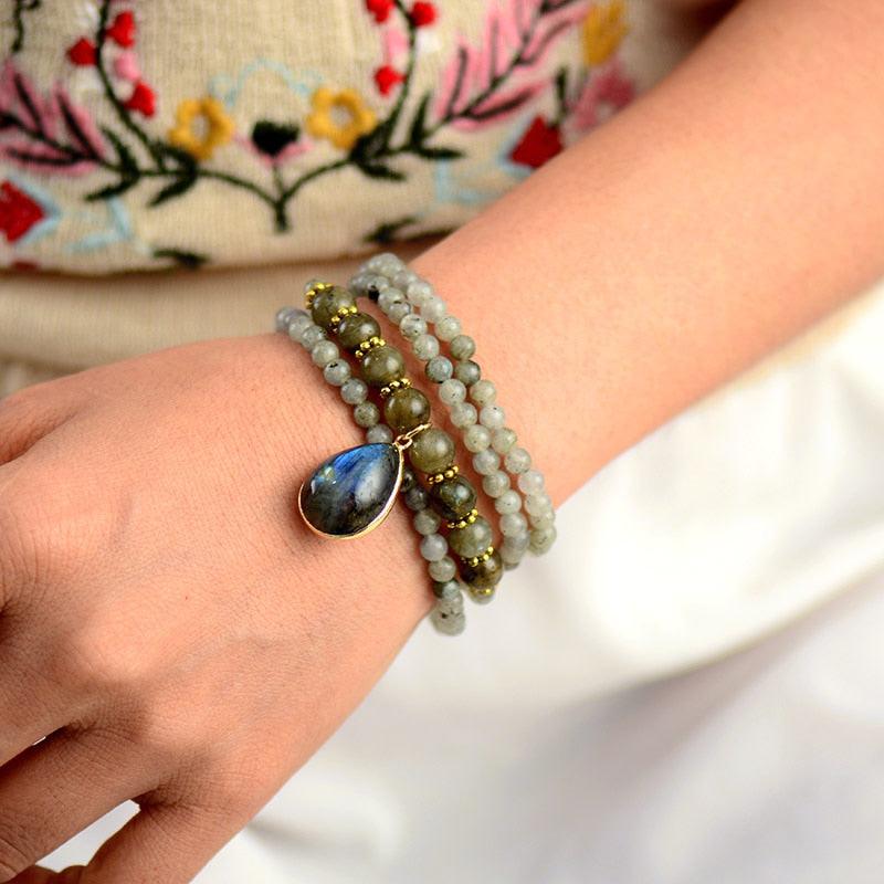Labradorite Serenity Wrap Bracelet–Necklace worn as a bracelet, showing iridescent blue and gold gemstone pendant with natural round beads and gold accents. ALLORA JADE