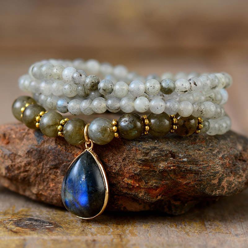 Handcrafted Labradorite Serenity Wrap Bracelet–Necklace coiled in a circle with iridescent teardrop pendant and mixed bead sizes on natural background. ALLOTA JADE