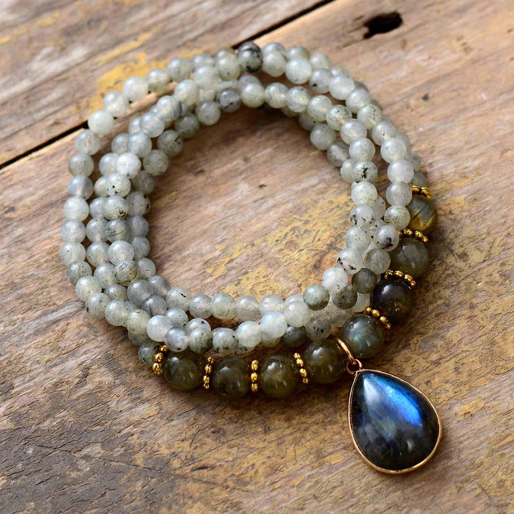 Handcrafted Labradorite Serenity Wrap Bracelet–Necklace coiled in a circle with iridescent teardrop pendant and mixed bead sizes on rustic wood background. ALLORA JADE