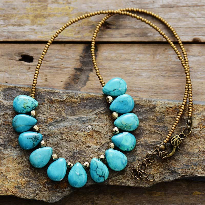 A Turquoise gemstone and seed bead necklace laid out on a wooden surface. ALLORA JADE