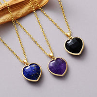 Heart pendant necklaces made with lapis Lazuli, Amethyst and Black Onyx, laying flat on grey background. ALLORA JADE