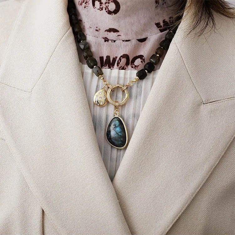 Necklace with black beads and gold pendants worn by a person in a beige blazer. Labradorite Pavé Statement Necklace | ALLORA JADE