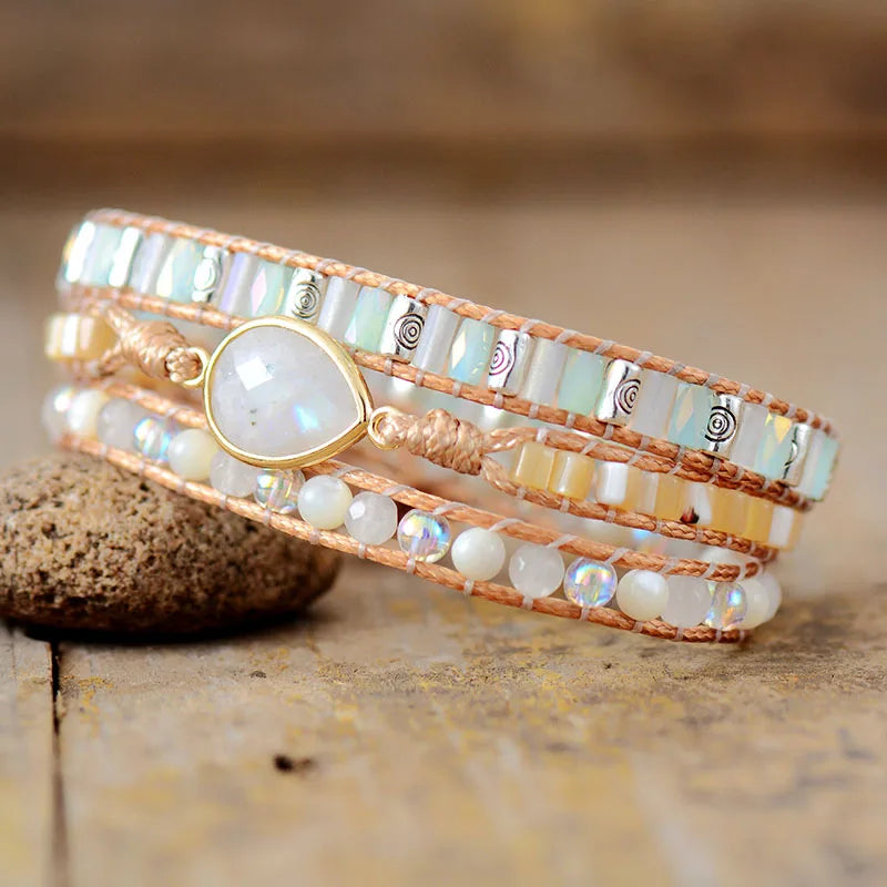 Multistrand beaded bracelet with a Moonstone central charm, displayed on a wooden surface