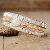 Multistrand beaded bracelet with a Moonstone central charm, displayed on a wooden surface