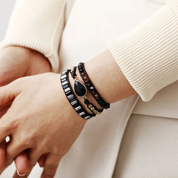 Close-up of a wrist wearing multiple bracelets black beaded bracelets with black Onyx charm. 