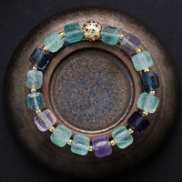 Multicolored beaded bracelet on a dark surface. Fluorite Faceted Cube Bracelet | ALLORA JADE