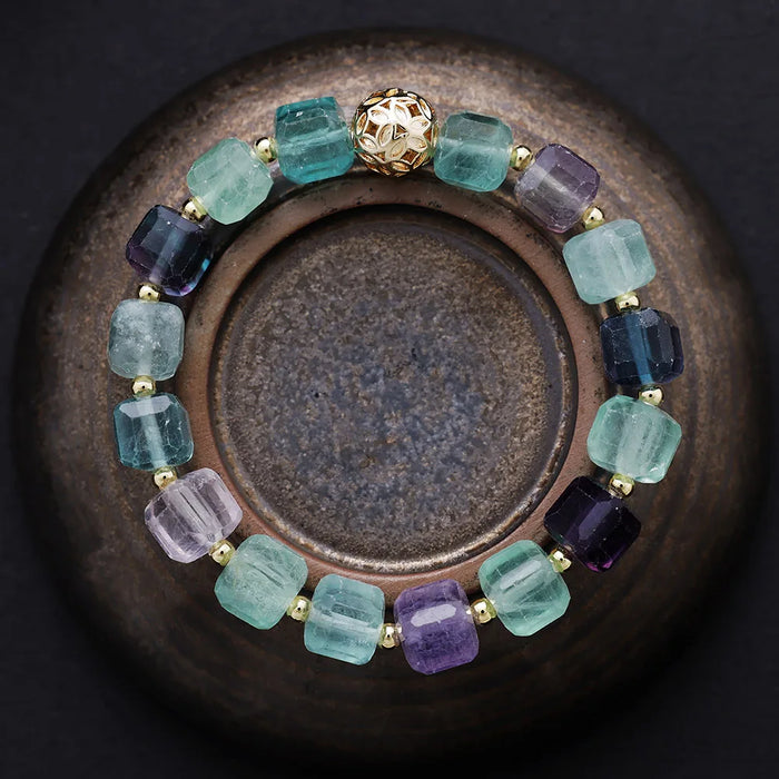 Multicolored beaded bracelet on a dark surface. Fluorite Faceted Cube Bracelet | ALLORA JADE