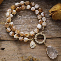 Beaded necklace with pendant on a wooden surface with dried leaves and stones. Citrine Pavé Statement Necklace | ALLORA JADE