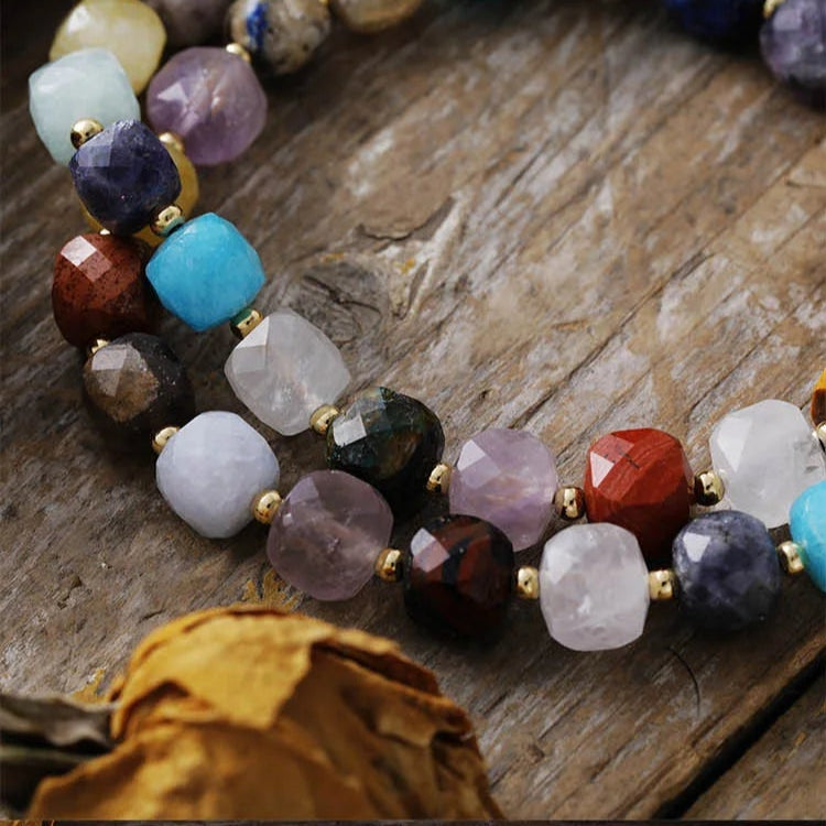 Beaded necklace on a wooden surface with dried leaves and stones. Chakra Crystal Pavé Statement Necklace | ALLORA JADE