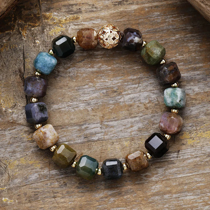 Multicolored beaded bracelet on a wooden surface. Indian Agate Faceted Cube Bracelet | ALLORA JADE
