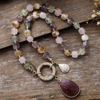 Multicolored beaded necklace with gold accents and a pendant on a wooden surface. Mixed Quartz Pavé Statement Necklace | ALLORA JADE