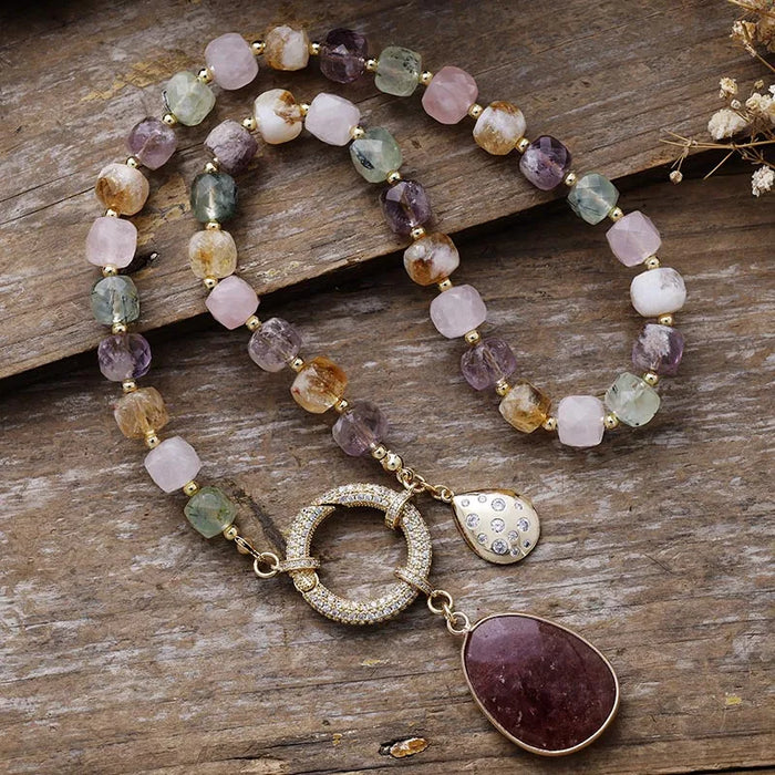 Multicolored beaded necklace with gold accents and a pendant on a wooden surface. Mixed Quartz Pavé Statement Necklace | ALLORA JADE