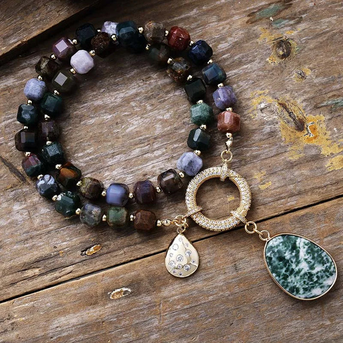 Multicolored beaded necklace with gold accents and pendant on a wooden surface. Indian Agate Pavé Statement Necklace | ALLORA JADE