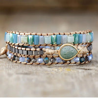 Multistrand beaded bracelet with a central Amazonite teardrop gemstone charm on a wooden surface