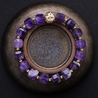 Purple beaded bracelet with gold accents on a dark surface. Amethyst Faceted Cube Bracelet | ALLORA JADE