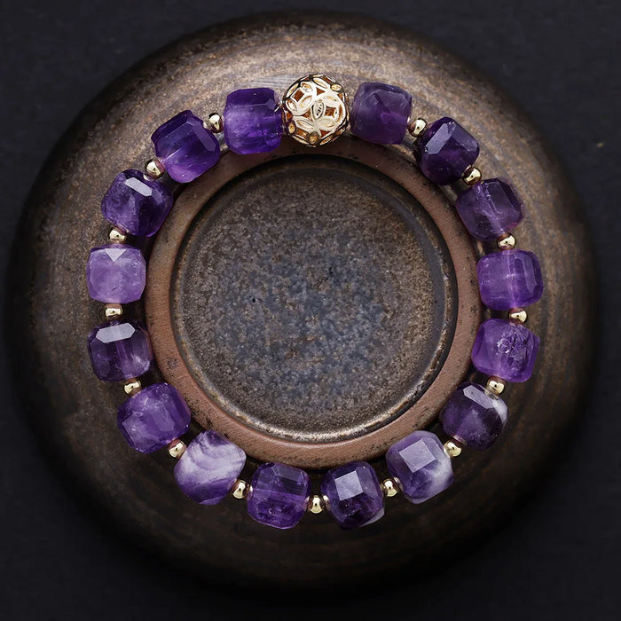 Purple beaded bracelet with gold accents on a dark surface. Amethyst Faceted Cube Bracelet | ALLORA JADE