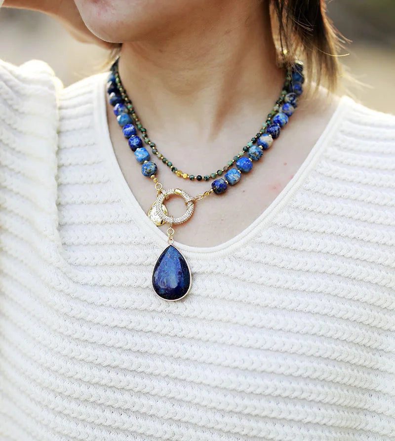 Close-up of a person wearing a blue teardrop pendant necklace on a white background. Lapis Lazuli Pavé Statement Necklace | ALLORA JADE