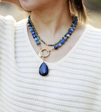Close-up of a person wearing a blue teardrop pendant necklace on a white background. Lapis Lazuli Pavé Statement Necklace | ALLORA JADE