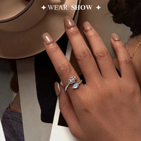 Close-up of a hand wearing a silver ring with a teardrop-shaped gemstone and Hamsa hand design