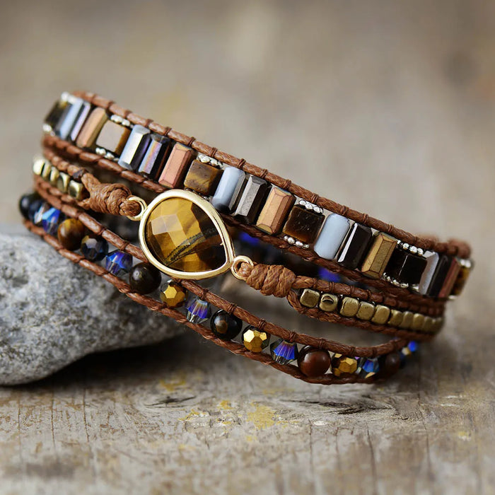Multistrand beaded bracelet with a prominent Tiger's Eye gemstone charm on a textured surface.