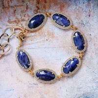 Gold bracelet with blue gemstones on a textured surface