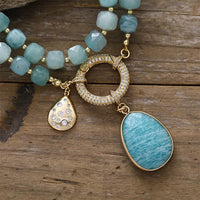Turquoise coloured beaded necklace with gold accents on a wooden surface. Amazonite Pavé Statement Necklace | ALLORA JADE