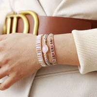Close-up of a wrist wearing multiple pink  beaded bracelets. 