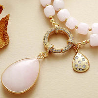 Necklace with pink beads and gold pendants on a beige background. Rose Quartz Pavé Statement Necklace | ALLORA JADE