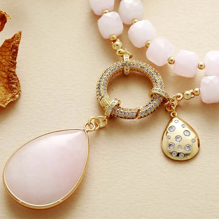 Necklace with pink beads and gold pendants on a beige background. Rose Quartz Pavé Statement Necklace | ALLORA JADE