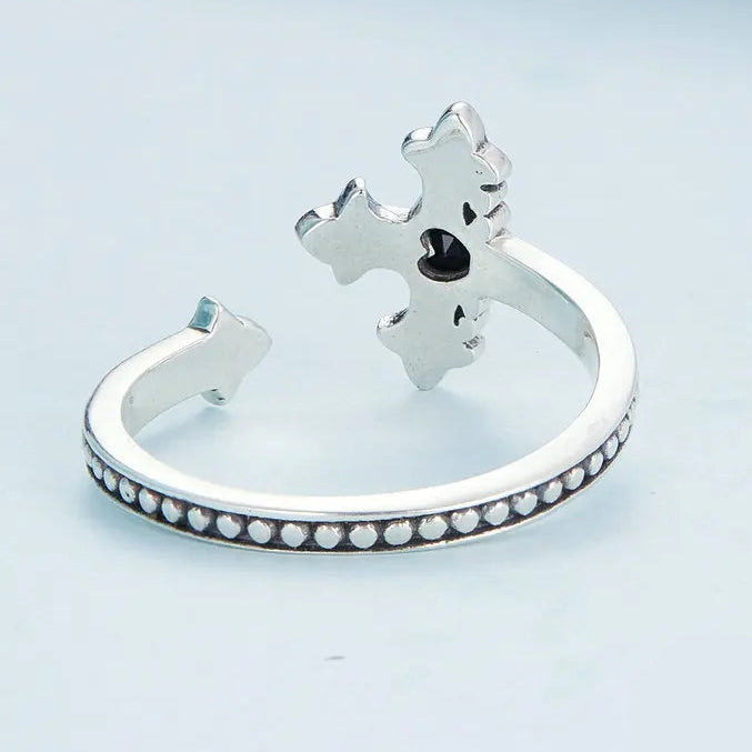 Display of a Cross silver ring from the back and underside on a light blue background.