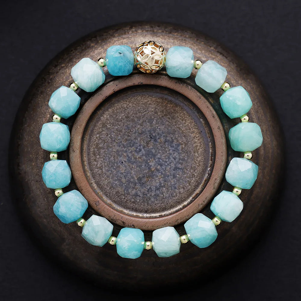 Aqua beaded bracelet with a gold clasp on a dark surface. Amazonite Faceted Cube Bracelet - ALLORA JADE