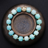 Aqua beaded bracelet with a gold clasp on a dark surface. Amazonite Faceted Cube Bracelet - ALLORA JADE