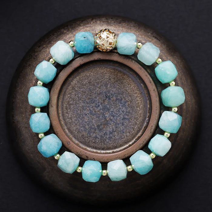 Aqua beaded bracelet with a gold clasp on a dark surface. Amazonite Faceted Cube Bracelet - ALLORA JADE