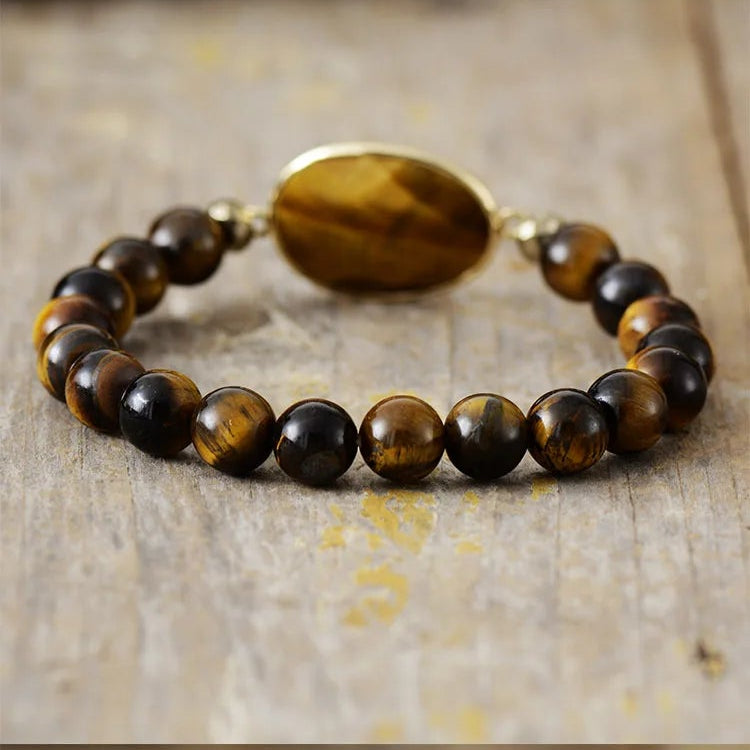 A stretchy bracelet with 8mm round Tiger's Eye beads and a faceted Tiger's Eye charm, displayed on a wooden surface.