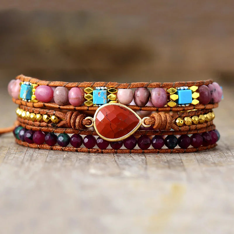 Multicolored beaded bracelet with a Red central stone, displayed on a wooden surface
