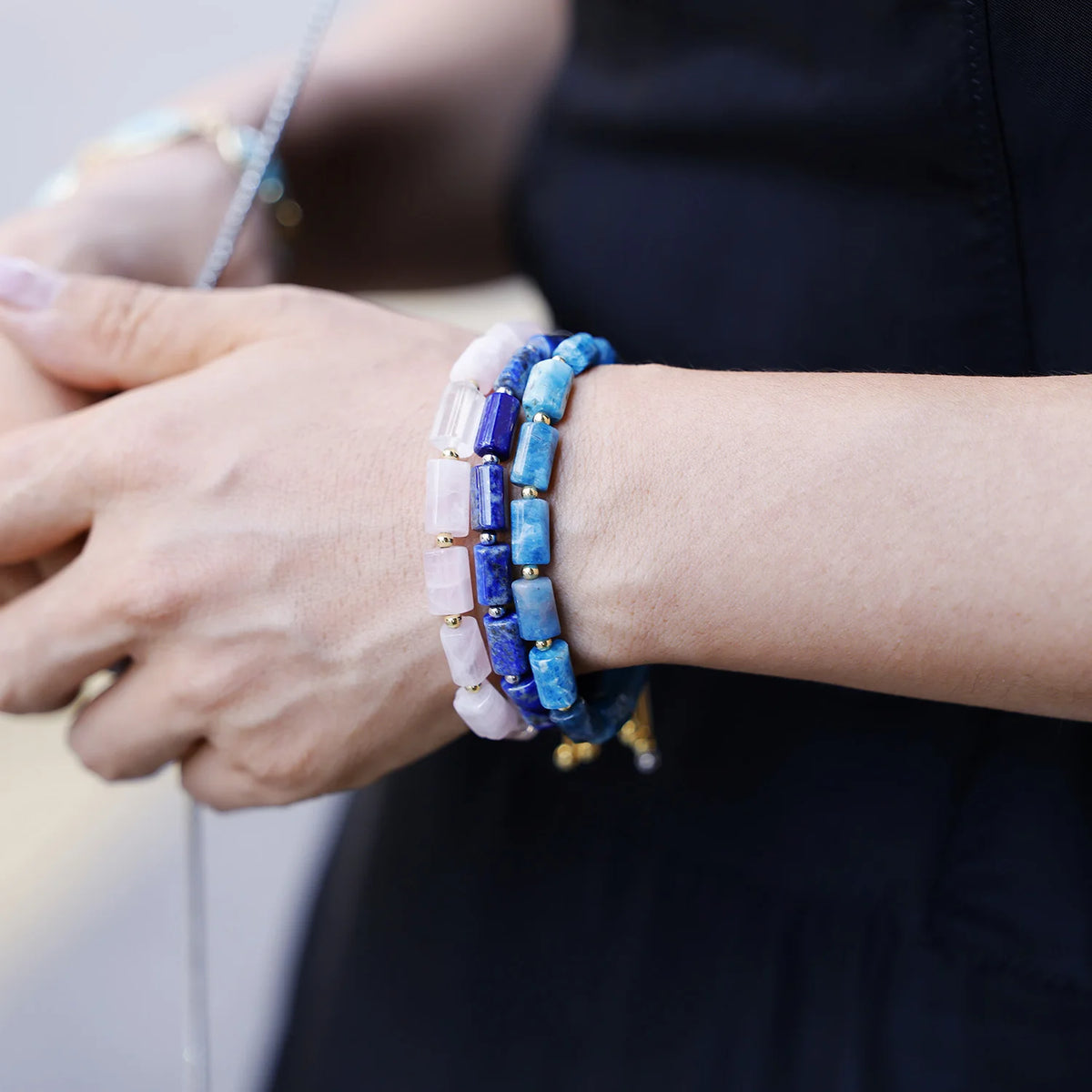 Close-up of a wrist wearing three beaded bracelets with a blurred background