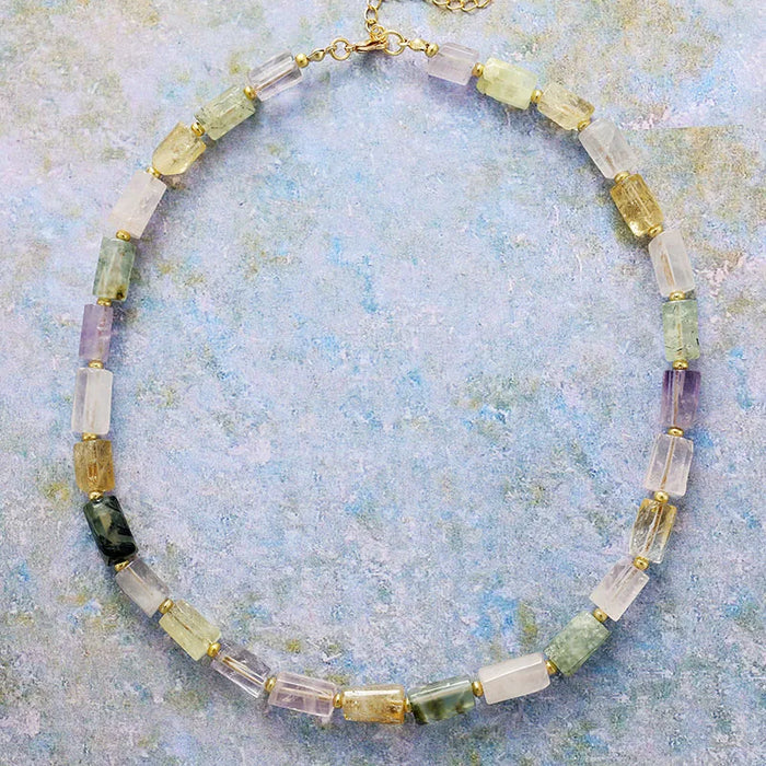 Multicolored beaded necklace on a textured blue background. ALLORA JADE