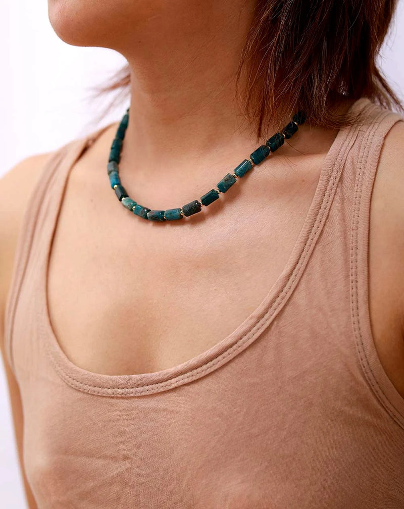 Person wearing a beige tank top and a green beaded necklace on a white background. ALLORA JADE
