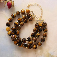 Brown beaded bracelet with gold accents on a light marble background