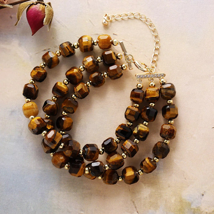 Brown beaded bracelet with gold accents on a light marble background