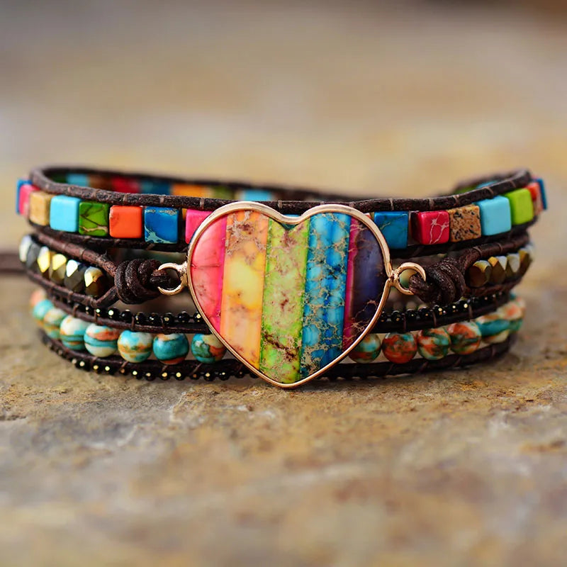 Multicolored beaded bracelet with a heart-shaped charm on a textured surface