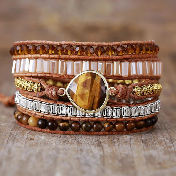 Multistrand bracelet with beads and a Tiger's Eye teardrop central stone on a wooden surface